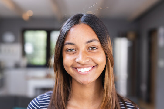 Portrait of happy biracial teenage girl smiling in kitchen