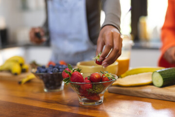 Diverse teenage female friends preparing healthy drink with fruit