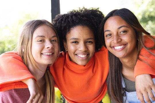 Portrait of happy diverse teenage female friends on balcony