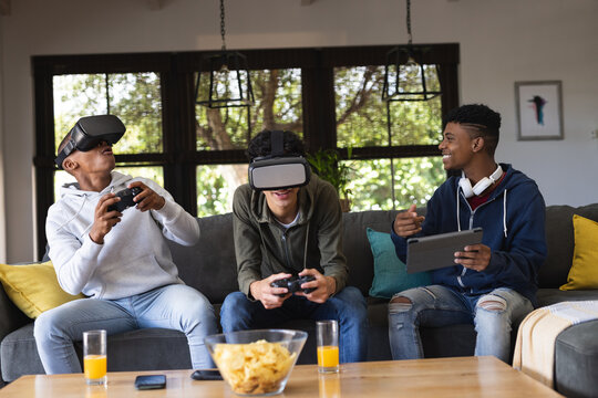 Image of happy diverse male teenage friends with vr glasses playing video games at home