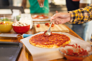 Hands of biracial teenage boy preparing pizza in kitchen