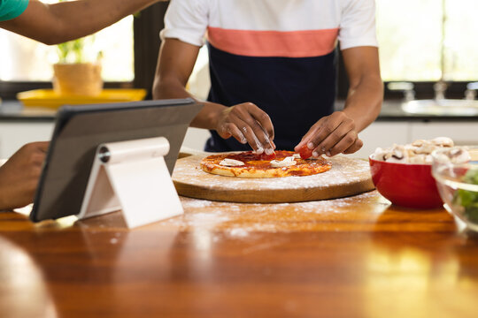 Hands of african american teenage boy preparing pizza in kitchen