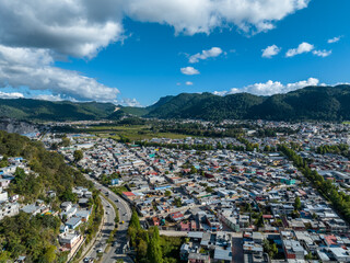 Aerial view of colorful mountain village of San Cristobal de Las Casas in Mexico. Clouds over the mountains. Panorama.