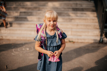 Schulkind am ersten Schultag steht vor der Schule