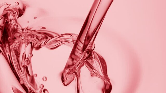 Macro crane shot of rose oil is being poured into rose oil on pale pink background | Abstract skin care cosmetics ingredients formulating concept