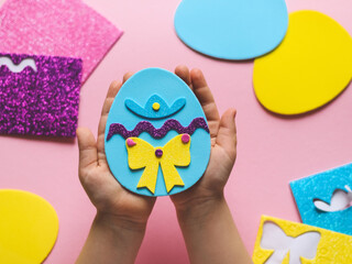 Fototapeta premium The hands of a little caucasian girl show the end result of a homemade felt easter egg
