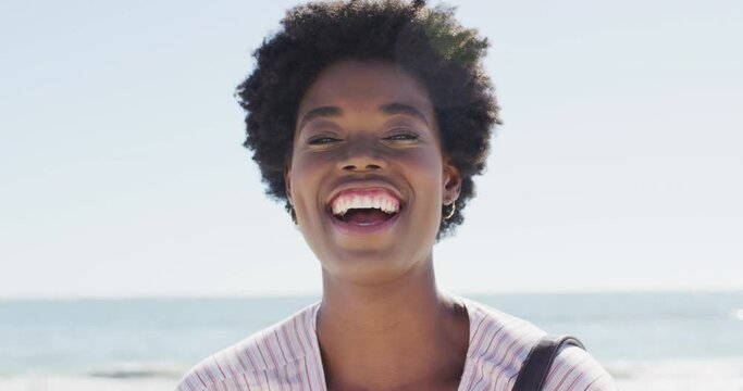 Video of face of happy african american woman looking at camera on beach