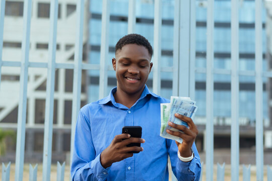 Businessman isolated over building standing sending money via phone with cash at hand