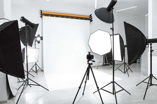 Tripod with camera and professional lighting equipment in modern photo studio