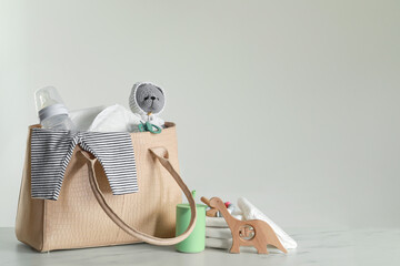 Mother's bag with baby's stuff on light grey background. Space for text