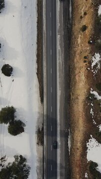 Aerial view of cars on the winter road within winter wilderness