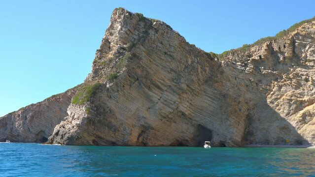 Rock geology layers visible at cliffs near Chomi or Paradise beach bay at Liapades, Greece, calm green sea in foreground. View from a boat