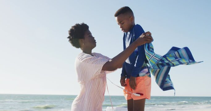 Video of happy african american mother covering son on beach