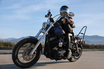 Fototapeta na wymiar Woman in helmet sitting on motorcycle outdoors