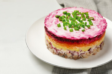 Herring under fur coat salad on white table, space for text. Traditional Russian dish