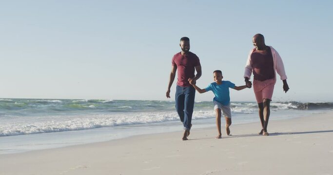 Video of african american happy african american grandfather, father and son walking on beach
