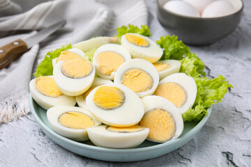 Fresh hard boiled eggs and lettuce on light grey textured table