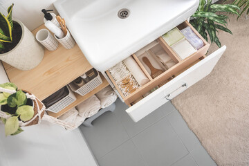 Bathroom under sink organizer drawers with neatly placed bath amenities and toiletries.