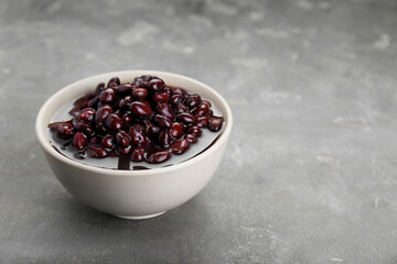 Bowl of canned kidney beans on grey table. Space for text