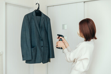 スーツに消臭スプレーをかける女性