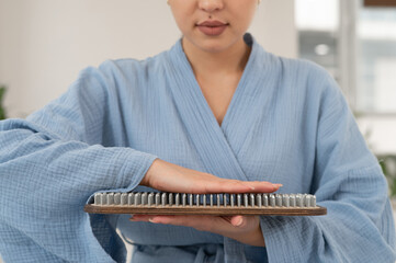 Asian woman touching Sadhu's wooden boards with nails.