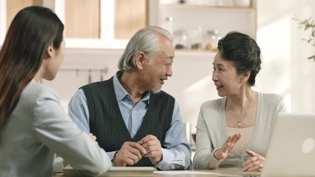 senior asian couple appears to be convinced and happy signing a paper document at home