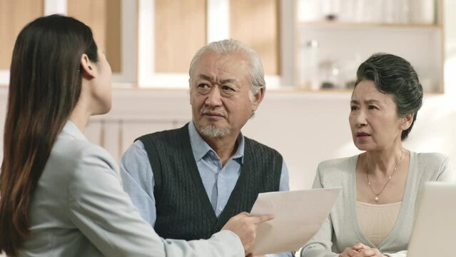 senior asian couple appears confused by and suspicious at a sales person selling financial product