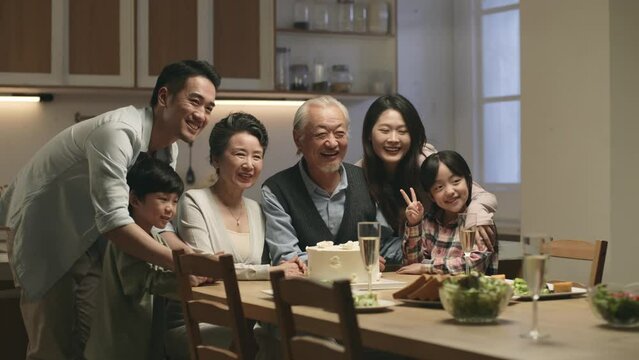 three generation asian family taking a group photo while celebrating grandma and grandpa's wedding anniversary