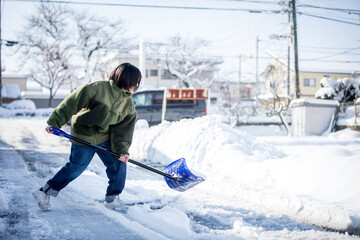 Fototapeta na wymiar 雪かきをする女性　shoveling snow