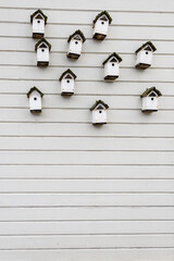 Collection of white wooden bird houses on the side of a white building
