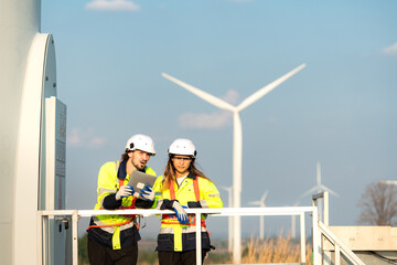 Man and female engineer stationed at the Natural Energy Wind Turbine site. with daily audit tasks of major wind turbine operations that transform wind energy into electrical electricity