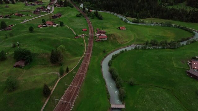 Aerial tilt up over railway tracks revealing an impressive valley of towering mountains in Switzerland. Lotschberg Tunnel in the Canton of Berne