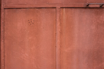 Texture of a rusty red metal door. Full-surface background with small details and borders.