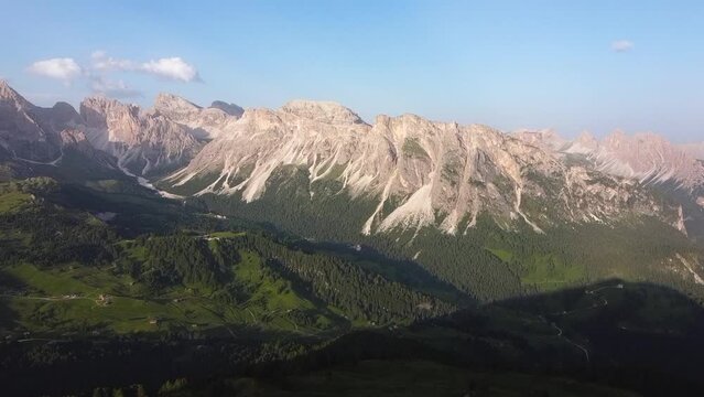 Reveal of Dolomite mountains lit by bright warm sunshine, aerial view