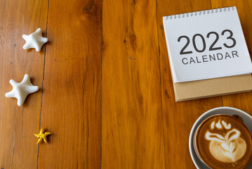 calendar 2023 and coffee cup on wood table, Top view and copy space. Xmas, Happy New Year, Goals, Resolution, To do list, Strategy and Plan concept