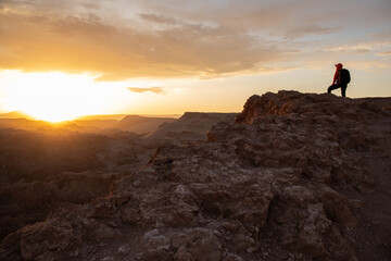 Hiker on a peak watching sunset Atacama desert, Chile, focus on the hiker