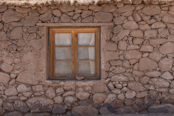 old wooden window in very old edged stone wall