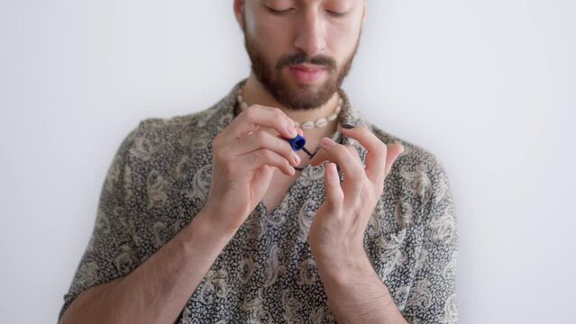 Young latin gay queer man concentrating painting his nails on a white background. 4k video.