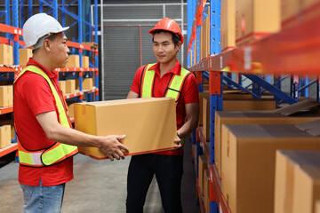 Group of warehouse workers men with hardhats and reflective jackets carrying a large box for delivery to production stock and inventory in retail warehouse logistics, distribution center