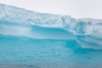 Beautiful shades of blue from a melting iceberg glacier floating in Antarctica sunlight