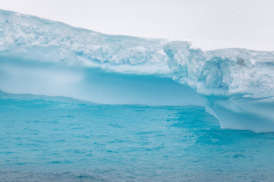 Beautiful shades of blue from a melting iceberg glacier floating in Antarctica sunlight © Rob Schultz