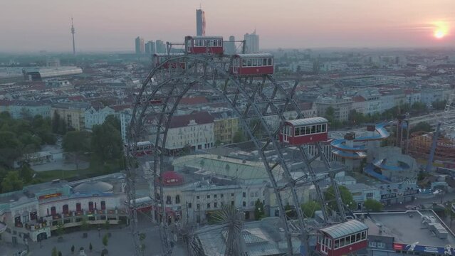 Aerial view, skyline of Vienna in the background of the Prater amusement park with ferris wheel and sunset.