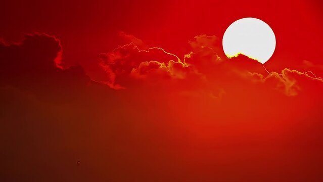 Timelapse of the sun rising over some clouds in a red sky