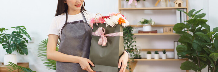 Flower shop concept, Female florist holding chrysanthemum and gerbera flower bouquet in gift bag
