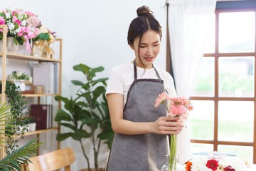 Flower shop concept, Female florist arrange pink gerbera and colorful flower in vase with happiness