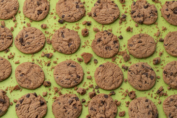 Trendy pattern made of chocolate chip cookies on green background.