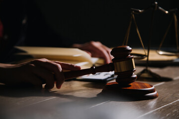 Obraz premium Justice and law concept.Male judge in a courtroom with the gavel, working with, computer and docking keyboard, eyeglasses, on table in morning light