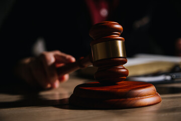 Justice and law concept.Male judge in a courtroom with the gavel, working with, computer and docking keyboard, eyeglasses, on table in morning light