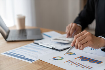 Young Asian businesswoman pointing document data graph and chart paper marketing and investment Statistical profit reports for financial, economic and financial growth. management and planning.