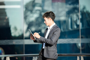 Male manager attending video conference and holding tablet, smatrphone and  cup of coffee in out side office